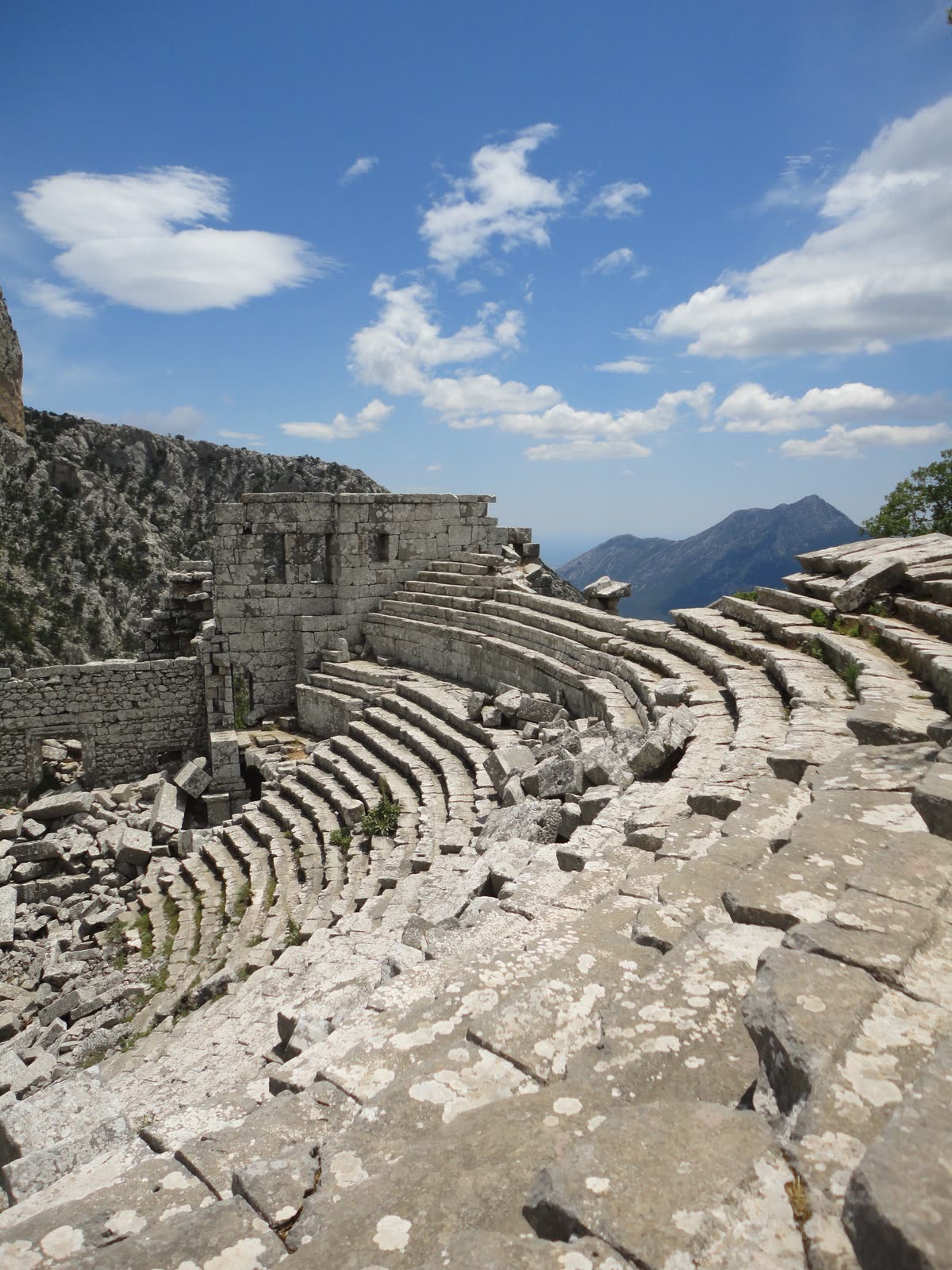 Stone tiers of a Roman amphitheatre under scattered cloud
