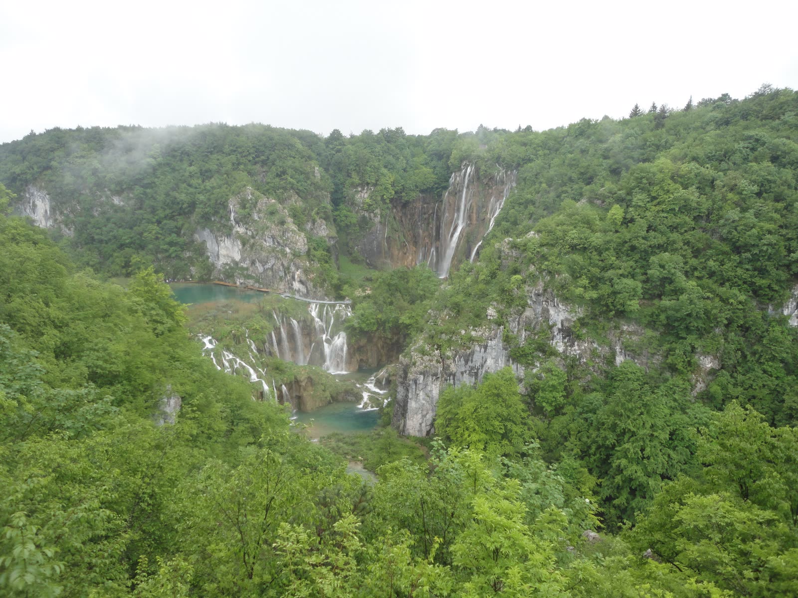 Terraced lakes and waterfalls in a forested gorge, seen from the rim