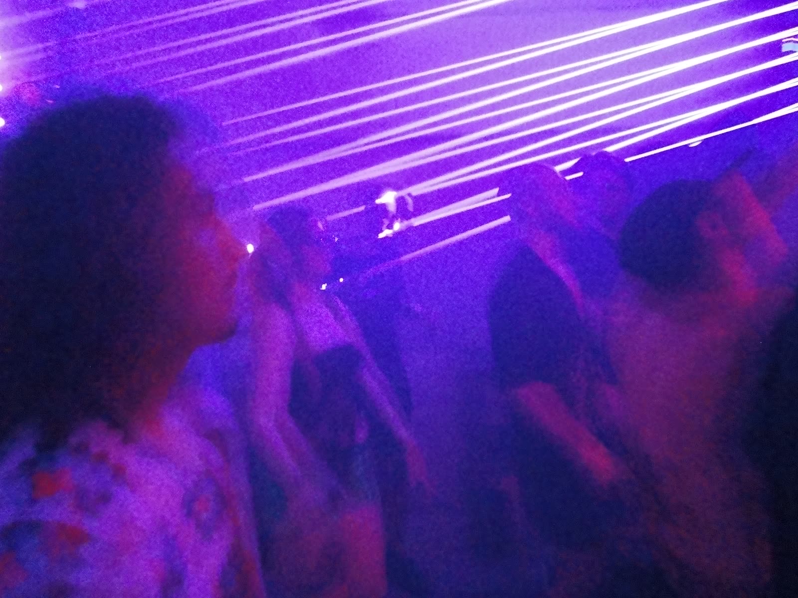 Purple laser beams cutting across a dark crowd