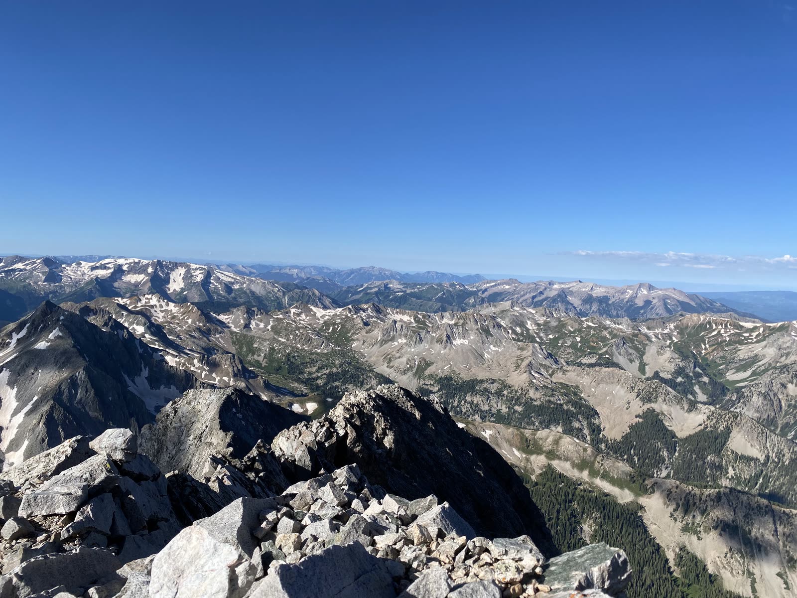 Snow-streaked peaks and granite ridgeline seen from a summit