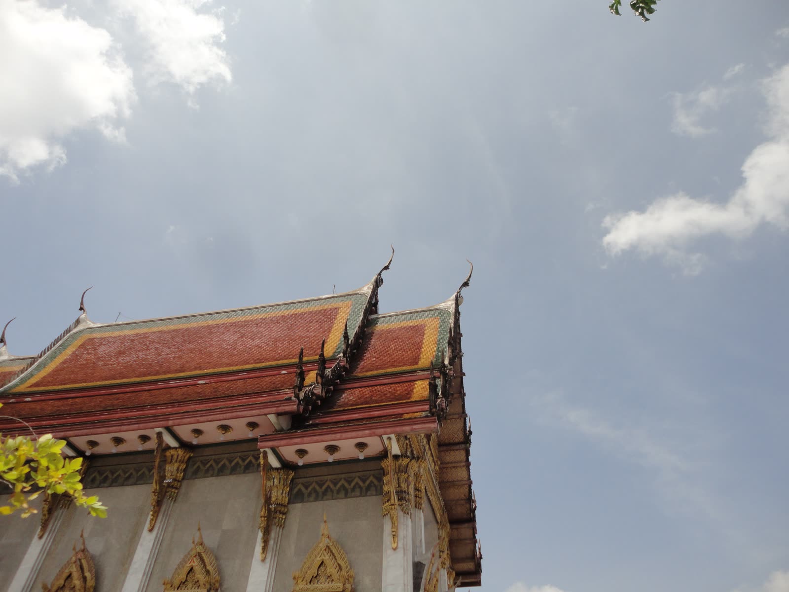 Tiled temple roof and gold finials against clouds